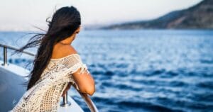 Woman leaning on cruise ship railing looking at the landscape.