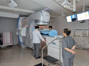 Medical professionals in scrubs assist a patient lying on a treatment table connected to a large Varian Edge radiotherapy machine.